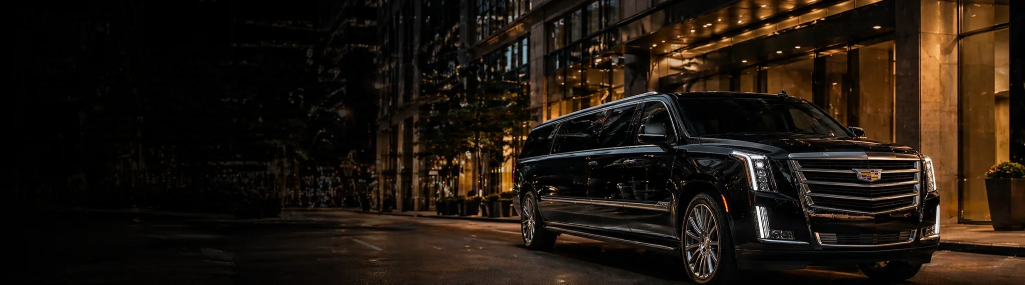 Black executive SUV outside a city hotel at night