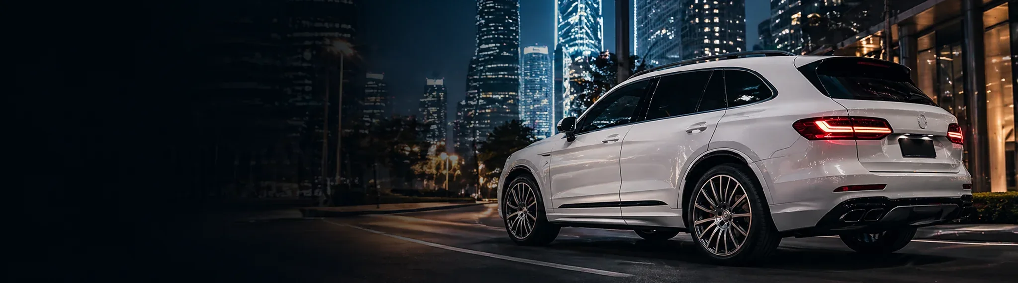 White luxury SUV on a city street at night